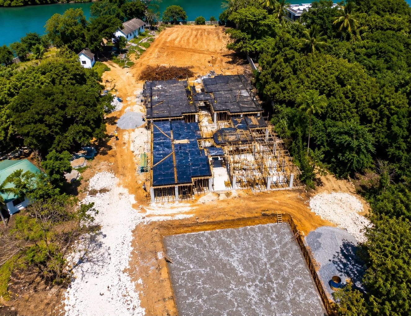 Aerial photograph of the Moorings Seaview Residence construction site in Mtwapa, showing cast floor slabs, column formwork and a poured foundation raft beside Mtwapa Creek.